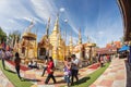 Buddhist people praying and walking around a golden pagoda.